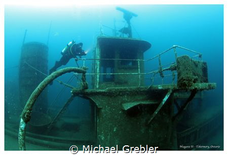 A diver checks her light before entering the wheelhouse o... by Michael Grebler 