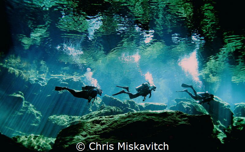 Divers heading back to the opening in Cenote.... by Chris Miskavitch 