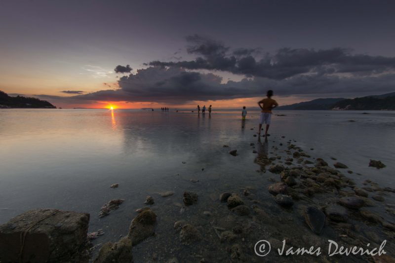 Follow the sun / Anilao low tide locals wander out in the... by James Deverich 