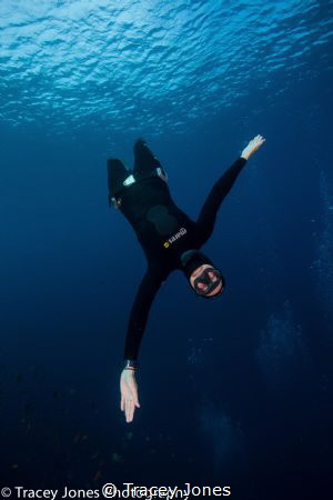 Free diver falling towards the camera with open arms by Tracey Jones 