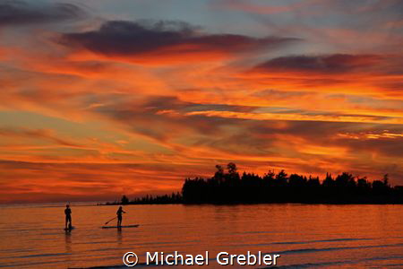 A couple share a quiet evening on stand-up paddle boards ... by Michael Grebler 