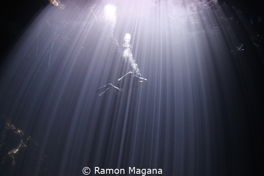 Cave diver through the sunlight in a cenote in Mexico by Ramon Magana 