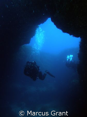 A diver going through Cirkewwa Arch on Malta's north west... by Marcus Grant 