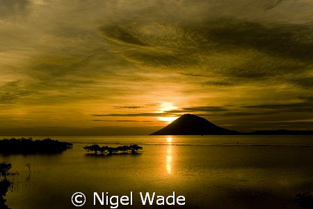 Sunset over Manado Tua. Pure Gold. by Nigel Wade 