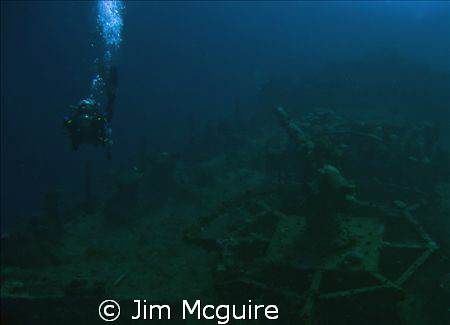Diver swimming passed an anti-aircraft gun on a sunken Ja... by Jim Mcguire 