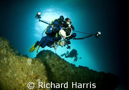 Photographers. Divers swimming into a sea cave in the Poo... by Richard Harris 