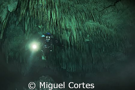 Diver into a big stalactites cave. by Miguel Cortes 