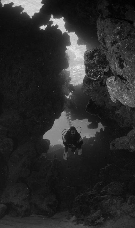 Diver in egypt entering a reef cave by Andy Kutsch 
