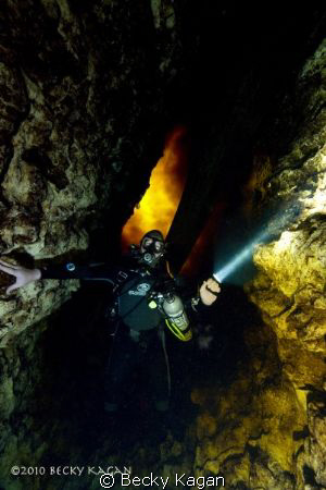 Cave diver descends down into the moulth of a cave with t... by Becky Kagan 