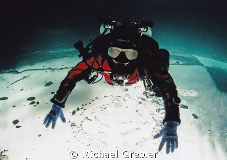 Technical diver on ice. Posed upside-down under the ice i... by Michael Grebler 