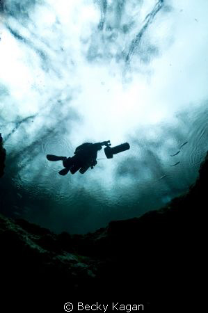 Cave Diver on a DPV gets ready to descend into the moulth... by Becky Kagan 