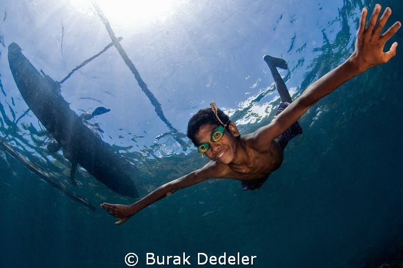 A young boy free diving from his dug out canoe with home ... by Burak Dedeler 