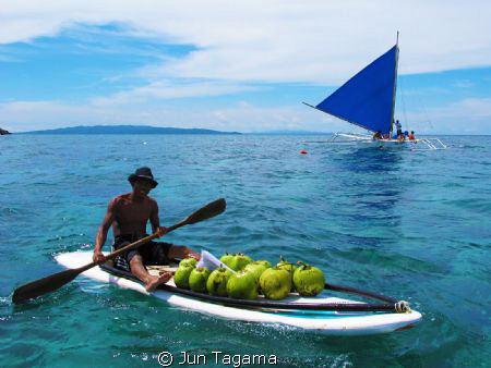 Selling coconut water to tourists under the heat of the s... by Jun Tagama 