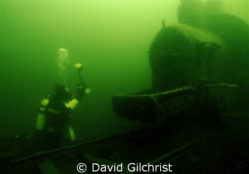 Diver prepares to take photograph of one of two locomotiv... by David Gilchrist 