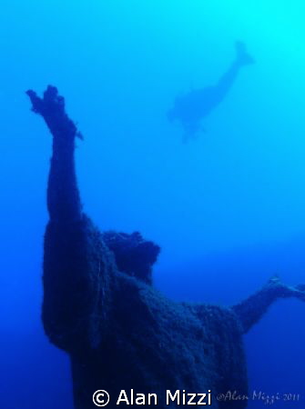 Diver swimming over statue of Jesus. by Alan Mizzi 