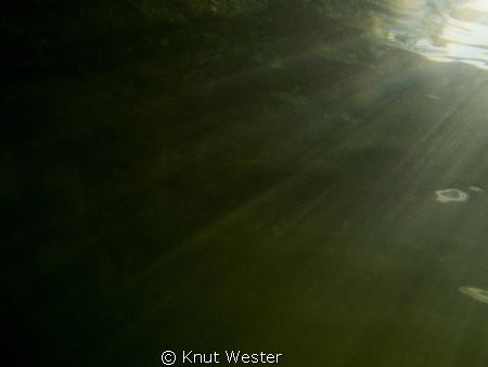 rays from the son hiting my canon g12 in a freshwater lake by Knut Wester 