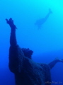 Diver swimming over statue of Jesus.