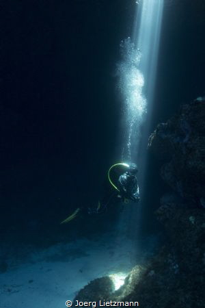 A sunbeam shines through an hole inside the comino caves. by Joerg Lietzmann 
