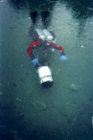 A diver with a DPV cruises underneath the translucent ice... by Michael Grebler 
