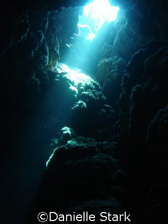 Inside of a cave, natural light streaming through the rocks. by Danielle Stark 