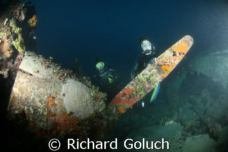 Two divers behind engine of the Flying Emily Boat-Truk La... by Richard Goluch 