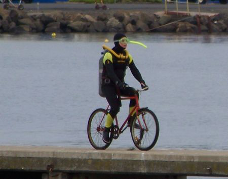 A diver riding a bike down a pier.  check out his massive... by Cal Mero 
