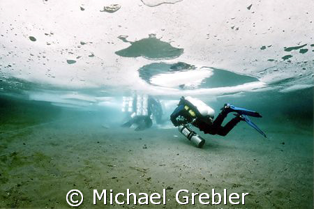 Ice divers, using cave dive techniques, proceeding to the... by Michael Grebler 