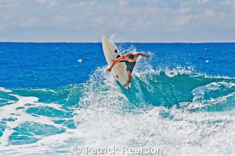 A surfer is frozen in time and space as he carves out the... by Patrick Reardon 