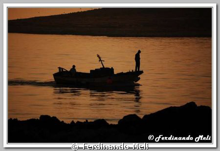 A boat in the sunset of the Mediterranea sea. by Ferdinando Meli 