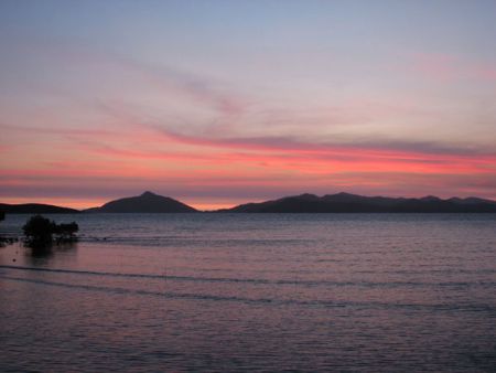 The sun sets off shore at Loloata Resort off the mainland... by Jerry Hamberg 