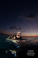 While swimming out for a shore dive at sunset, I asked my friend to pose for me.  I balanced one strobe on top of my head to give her face fill light, and placed the other strobe under the water to illuminate her tank and octo. 