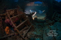 Look closely: a diver is lit by a remote slave strobe as he explores the interior of the Nicholson shipwreck. The WW II landing vessel lies in 55' of water in Grand Cayman. 