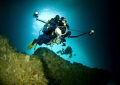 Photographers. Divers swimming into a sea cave in the Poor Knights Islands, New Zealand.