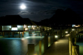 Resort huts over water with main island of Bora Bora in background.